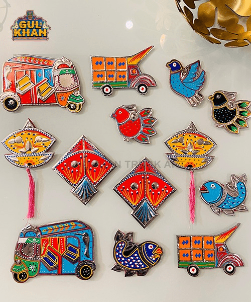 Colorful traditional truck and bird magnets with kite and diya designs on white background