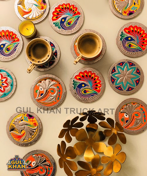 Colorful round coasters with intricate bird and floral designs surrounding two cups of coffee and a small candle on a beige surface