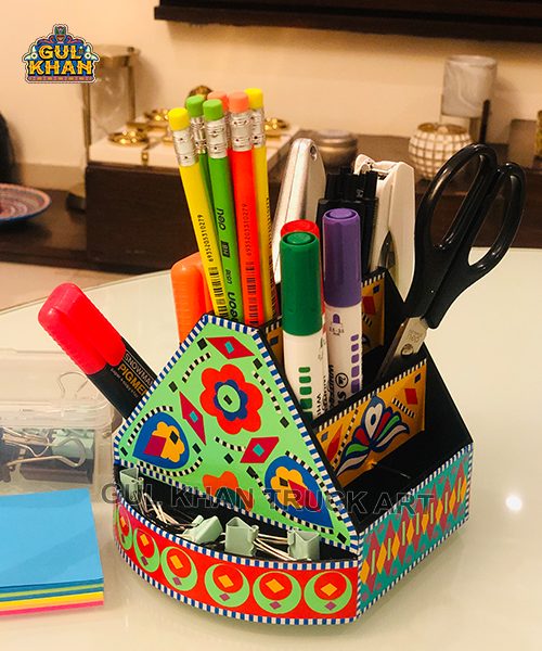 colorful traditional truck art style desk organizer holding pens, markers, scissors, and pencils on a table