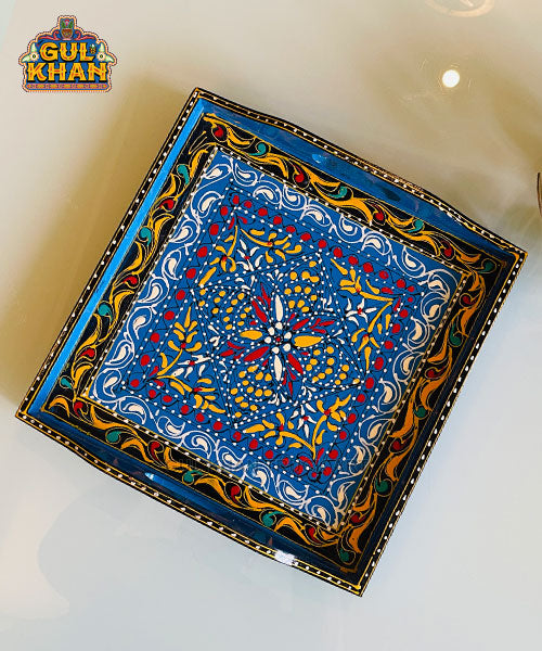square ceramic plate with blue, red, yellow, and white floral and swirl patterns, ornate decorative border