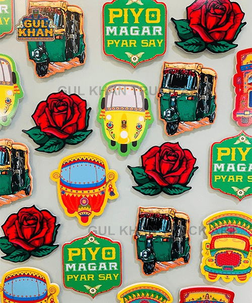 Colorful acrylic fridge magnets featuring auto rickshaws, red roses, and signs with Urdu text on white background