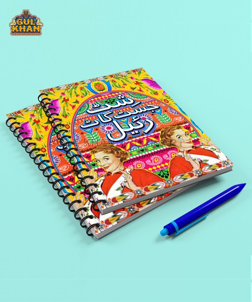 Colorful spiral-bound notebooks with vibrant truck art design and Urdu text, paired with a blue pen on light blue background