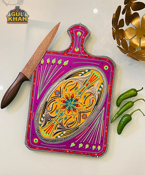 Colorful Gul Khan decorative cutting board with intricate patterns, kitchen knife, green chilies, and golden bowl