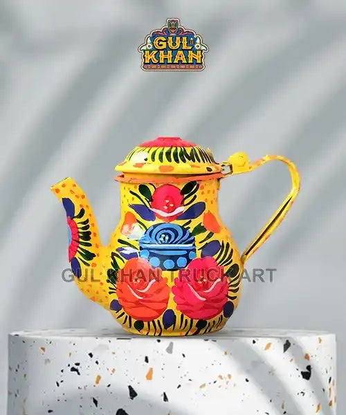 Yellow hand-painted metal teapot with vibrant floral patterns displaying red, blue, and black colors