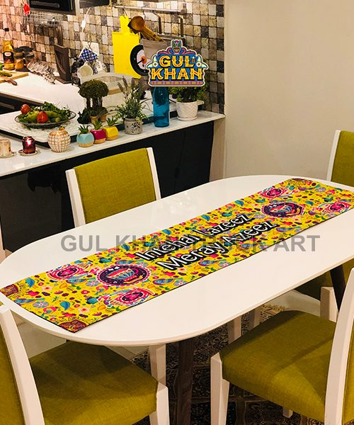 Bright yellow floral table runner with colorful patterns on white dining table with green upholstered chairs