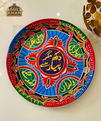 Colorful circular truck art plate with Urdu calligraphy and floral patterns on white wall