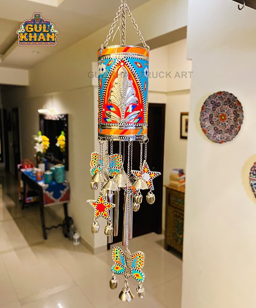 Colorful hand-painted traditional wind chime with butterflies, stars, and bells hanging indoors