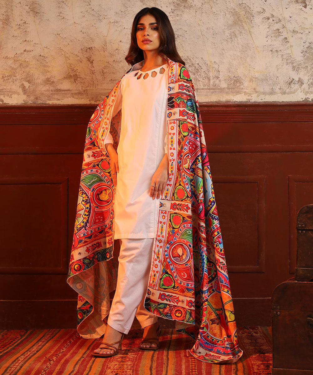 Woman wearing white kurta pajama with colorful printed stole in an indoor setting with textured walls
